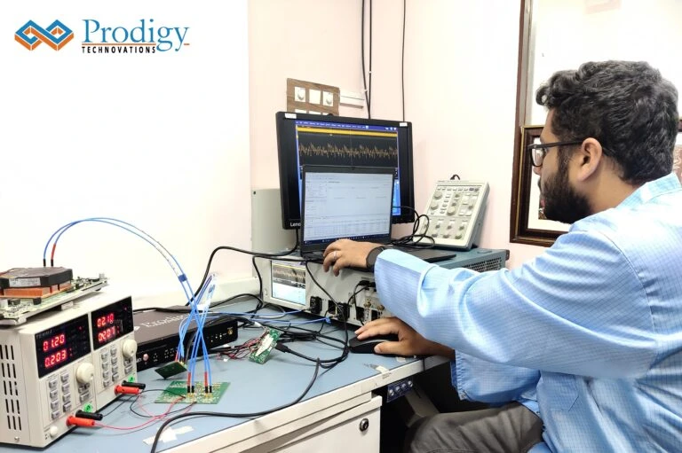 An engineer in a blue lab coat sits at a desk using a laptop and a Tektronix oscilloscope to analyze data from a Prodigy Technovations Automotive Ethernet Protocol Analyzer connected to testing hardware.